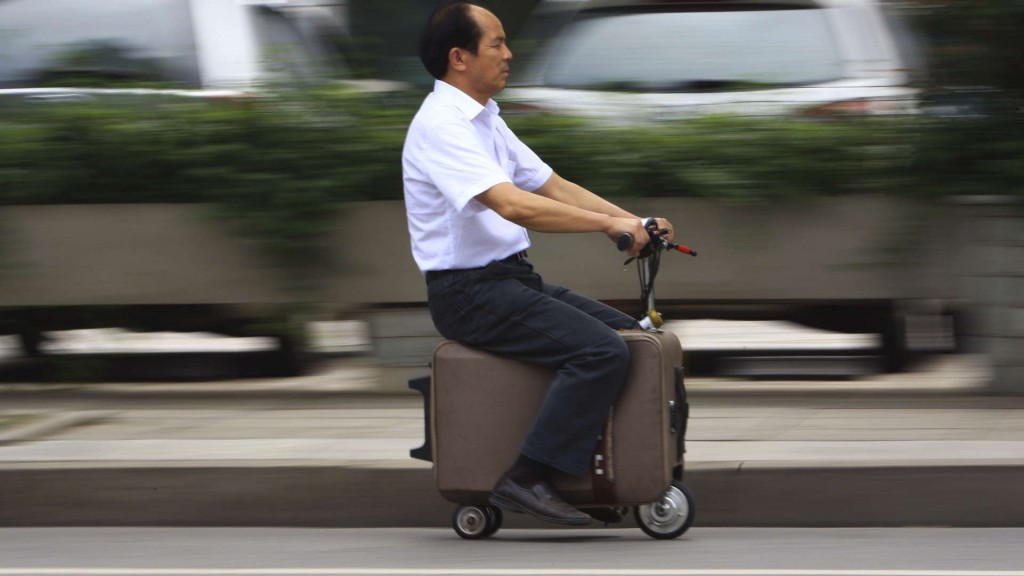 He Liang rides his home-made suitcase vehicle along a street in Changsha